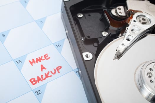 Make a backup of hard disk reminder. Calendar with text and hard drive. Selective focused on text backup and magnetic head.