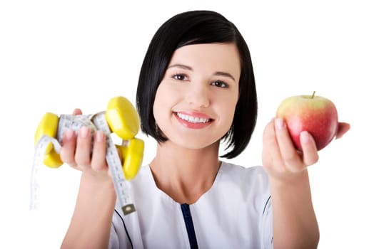 Woman dietician holding apple and dumbbells with measuring tape