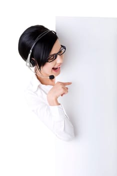 Pretty young call center worker wearing a headset and holding blank sign board
