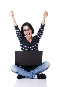 Happy young woman with fists up using her laptop, isolated on white.