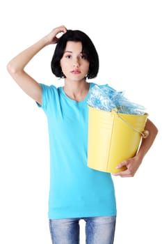 Young beautiful woman with trash bin, full of recycling plastic, thinking and scratching her head