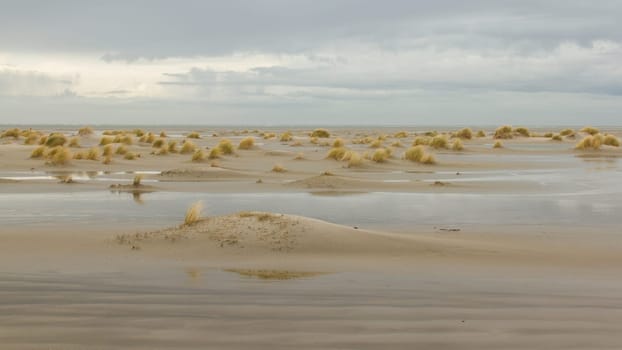 Low tide at the dunes of Ameland, dark sky, Holland