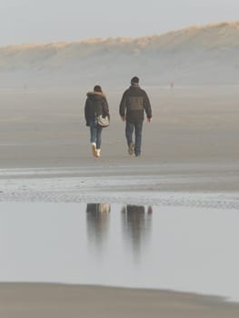 Couple walking on a dutch beach in the winter