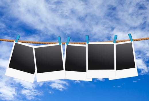 Five empty instant photos hang on the clothesline against a blue sky