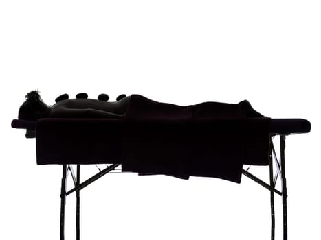 one woman lying on a massage table in silhouette studio on white background
