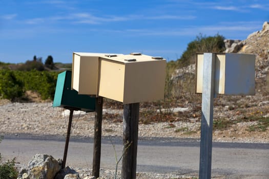 Individual mailboxes on wooden poles stand alone at the roadside