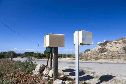 Individual mailboxes on wooden poles stand alone at the roadside