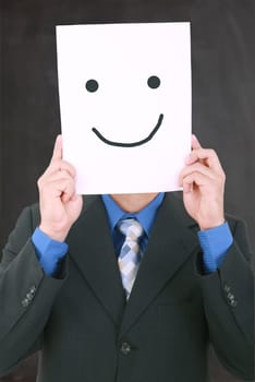 Young businessman hiding his face with a white billboard with a smiley face on it