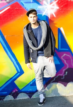 Full body shot of young man standing in front of graffiti