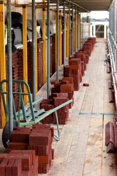 red bricks and wheelbarrow on  scaffolding