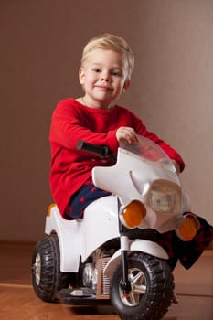Portrait of Happy Boy posing on Toy Motorcycle