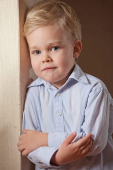 Portrait of little boy in shirt standing at the wall