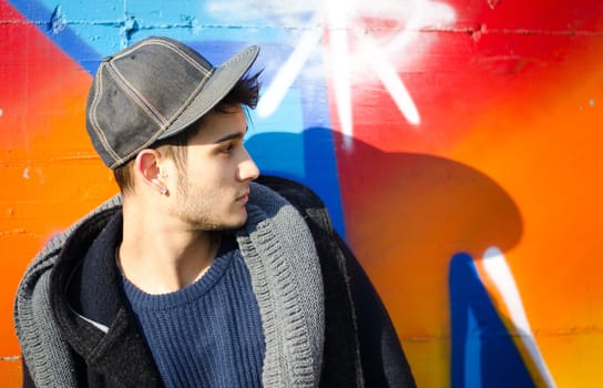 Handsome young man against colorful graffiti covered wall