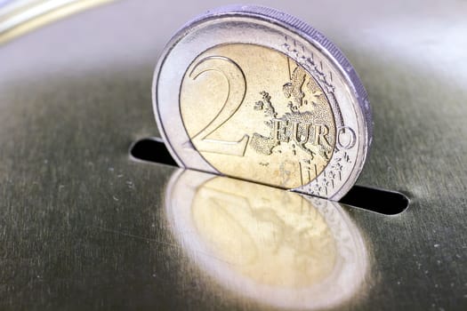 Two-euro coin inserting it into a piggy bank as savings