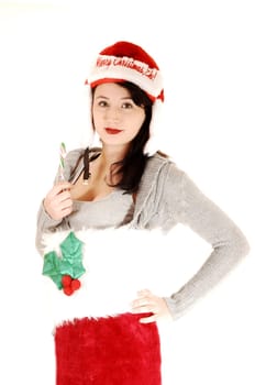 A very pretty young woman in a Christmas stocking and a Santa Claus hat holding up a candy cane, for white background.