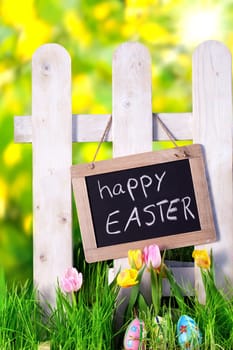 happy easter chalkboard on fence in spring