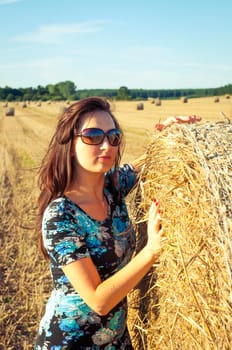 An image of brunette girl portrait and straw bale