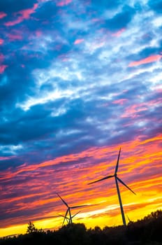A silhouette of windturbines on a amazing sunset