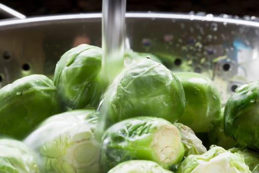 Close up of brussels sprouts being rinsed in colander