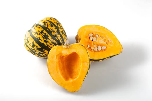 Cut and whole winter squash on white background with shadows.