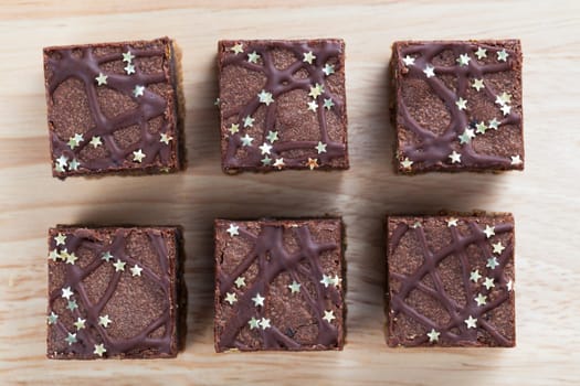 Six chocolate brownies sprinkeled with silver stars from directly above