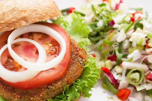 Delicious and healthy quinoa burger topped with a tomato slice and onions