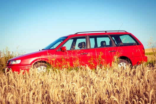 Red car parked near the wheat field