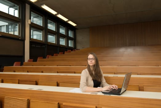 A young student sits alone with a notebook in the lecture hall
