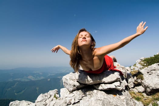 A young woman lies on rocks and floats lightly into the sky