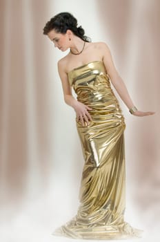 Young elegant slender woman as a statue in dress made of gold