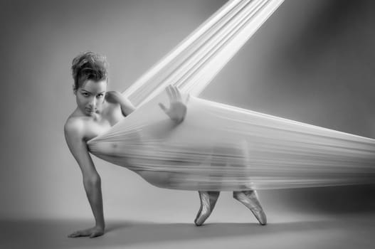 Female nude in black and white of a ballet dancer supported with stretch cloth