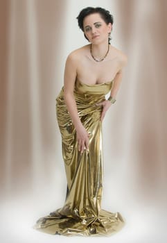 Young elegant slender woman as a statue in dress made of gold