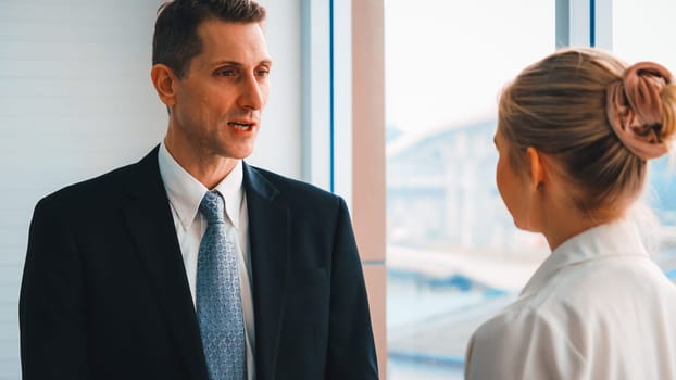 Two business people talk project strategy at office meeting room. Businessman discuss project planning with colleague at modern workplace while having conversation and advice on financial report. Jivy