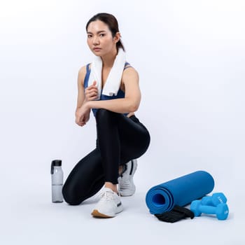 Athletic and sporty asian woman resting after intensive cardio workout training. Healthy exercising and fit body care lifestyle pursuit in studio shot isolated background. Vigorous