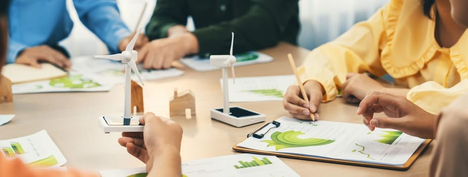 Green business meeting represented renewable energy. Skilled businesspeople discuss green business investment at table with environmental documents. Closeup. Focus on hand. Delineation.