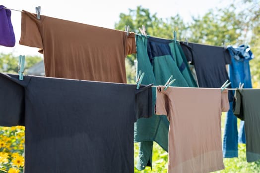 Wet laundry hanging on the rope, colorful clothing in the garden