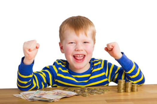 Cheering boy sitting in front of coins and bills
