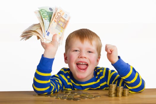 Cheering boy with banknotes in hand,sitting in front of coins