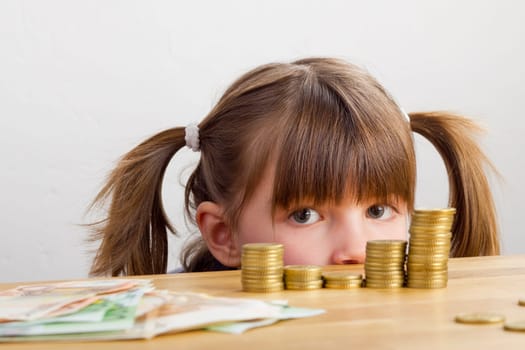Girl looking at money towers - lying on the table