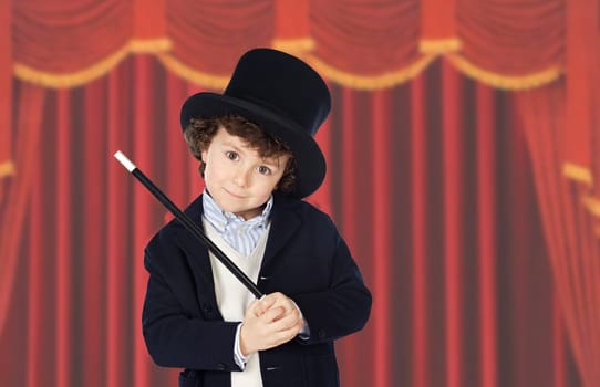 Adorable child dress of illusionist with hat and red curtains of background