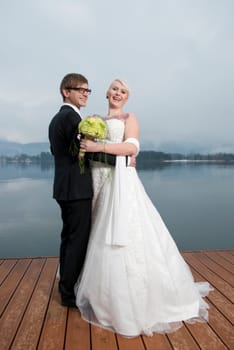 Young blonde bride with a tattoo on her chest and her groom standing next to each other