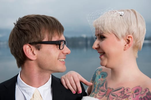 Portrait of a young blonde bride with a tattoo on her chest and her groom