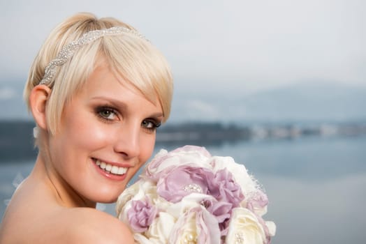 Portrait of a young blonde smiling bride with hair accessories and bridal bouquet