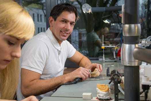 Dental technicial with a handpiece in a dental lab polishing the model of a prosthesis.