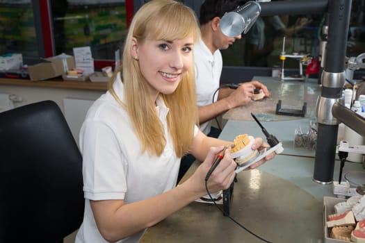 Dental technicial applying wax to a prosthesis model in an articulator