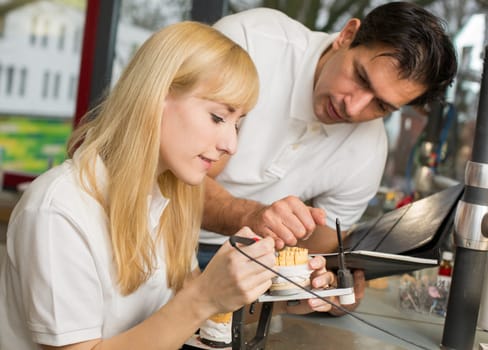 Dental technician instructing an apprentice in producing a dental prosthesis