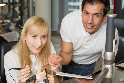 Dental technician instructing an apprentice in producing a dental prosthesis