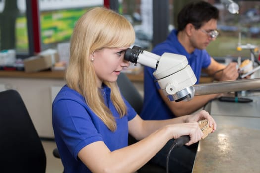 Dental technician producing a prosthesis under a microscope