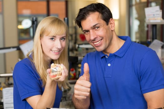 Dental technicians presenting dental prosthesis and showing thumbs up
