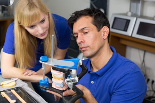 Two dental technicians looking at articulator in a dental lab